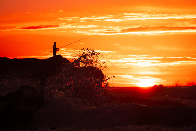 Sunset silhouette of a fisherman on the rocks near Tamraght
