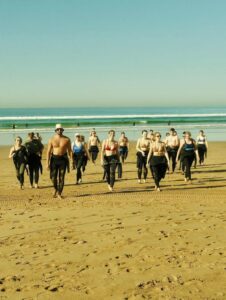 Surf lesson group in wetsuits warming up on the beach
