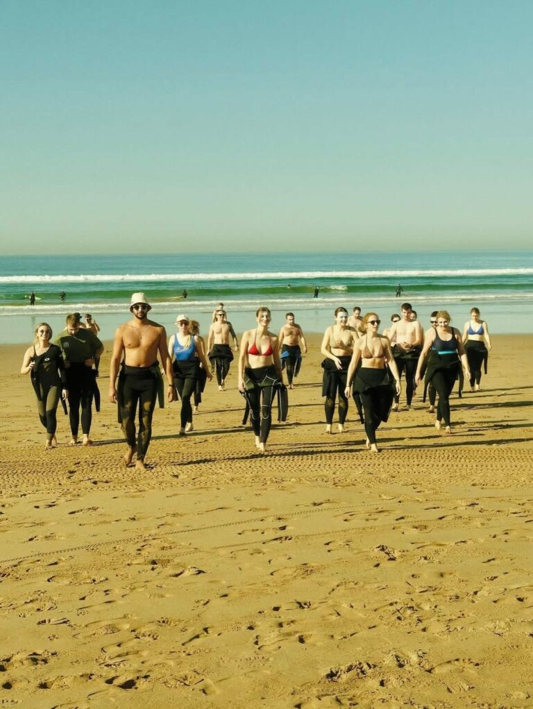 Surf lesson group in wetsuits warming up on the beach