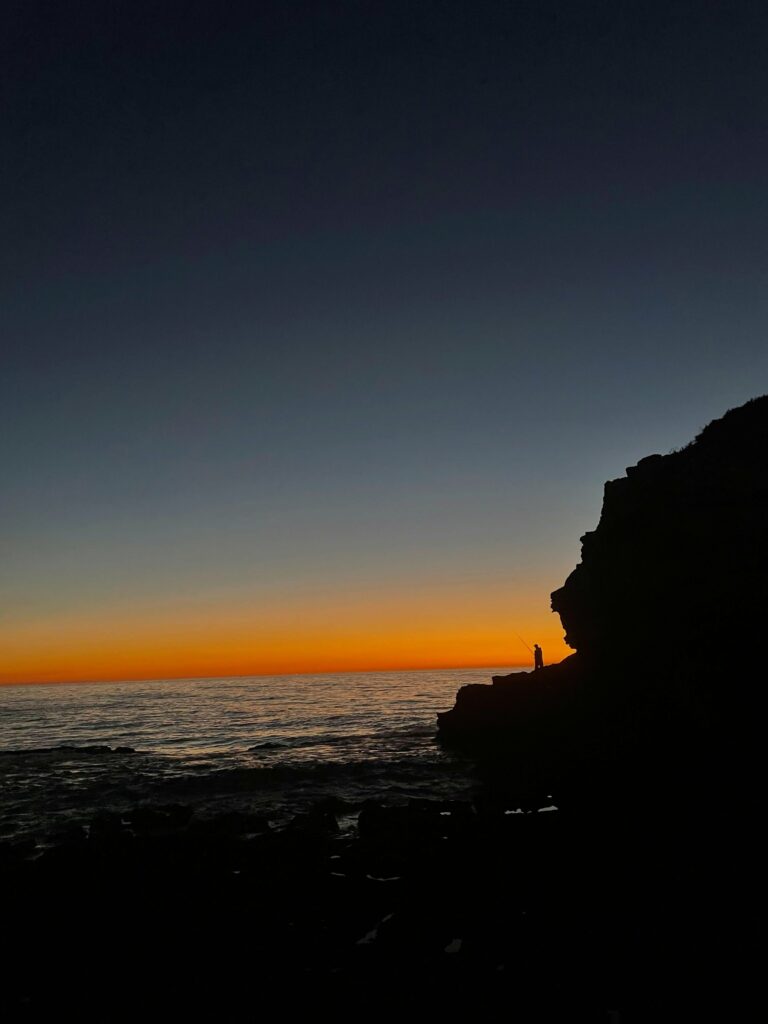 Sunset silhouette of the cliffs over the ocean near Tamraght