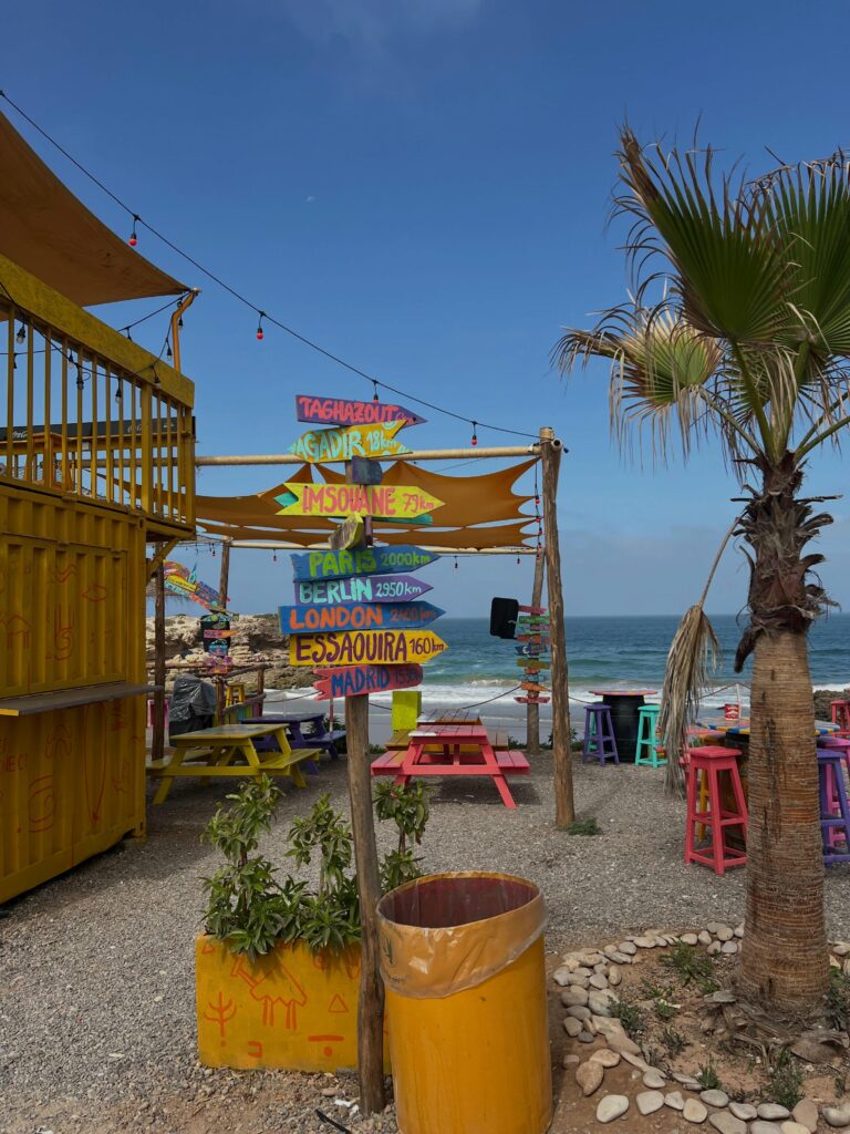 Beach café with colourful parasols and a palm tree in Taghazout Bay
