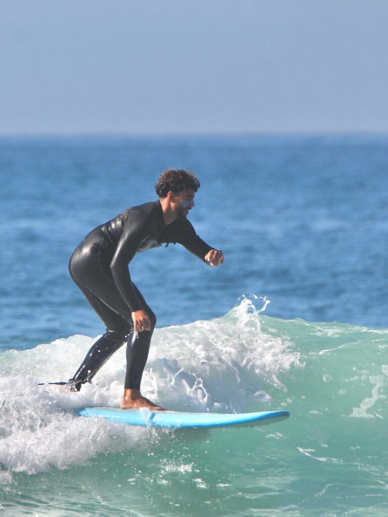 Surfer riding a wave on a sunny day in Taghazout Bay