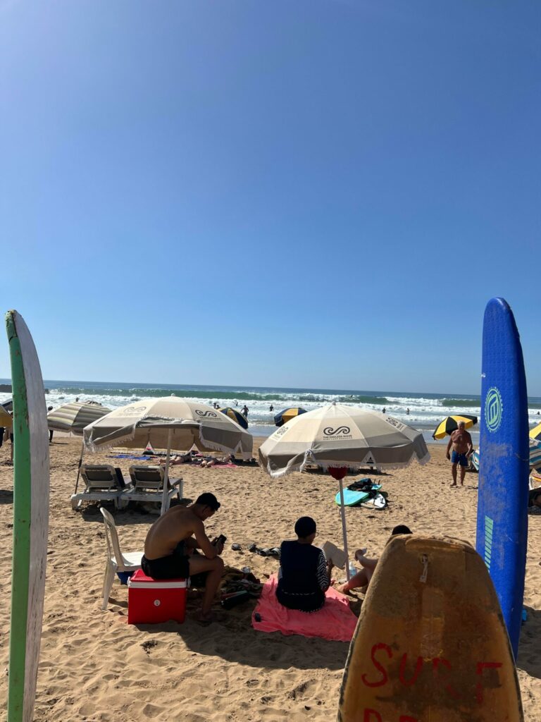 Surfboards and umbrellas on a sunny beach day near Tamraght